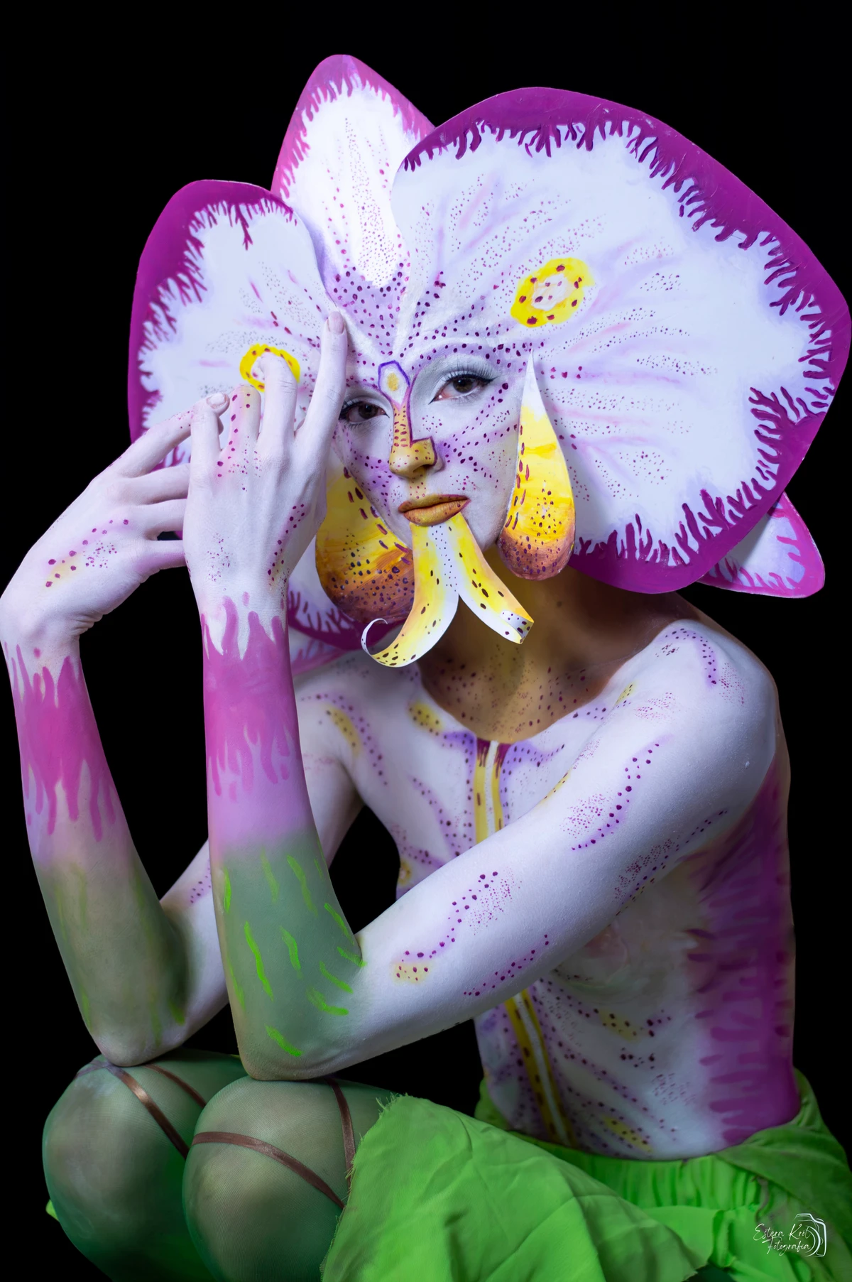 Portret studyjny kobiety w artystycznym makijażu inspirowanym orchideą na czarnym tle